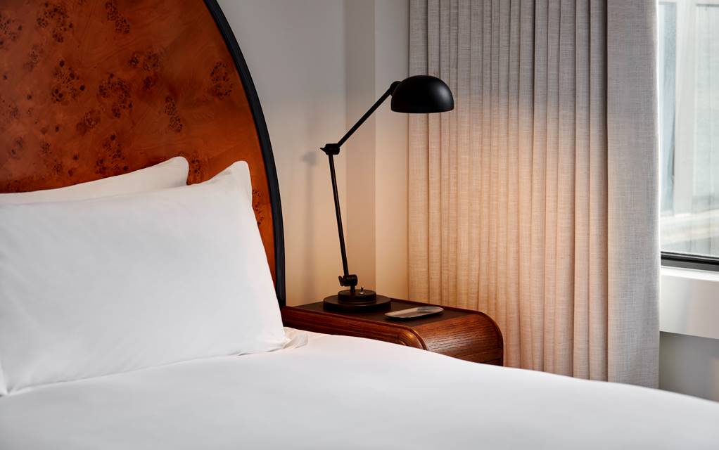 Detail of bed with bedside lamp at a Lyle hotel room.