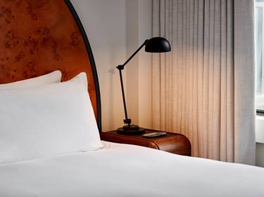 Detail of bed with bedside lamp at a Lyle hotel room.