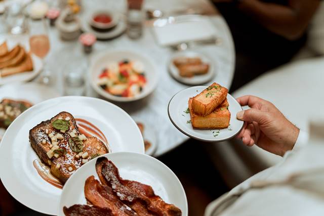 Waiter hands carrying plates of breakfast food to table at Lyle brunch.