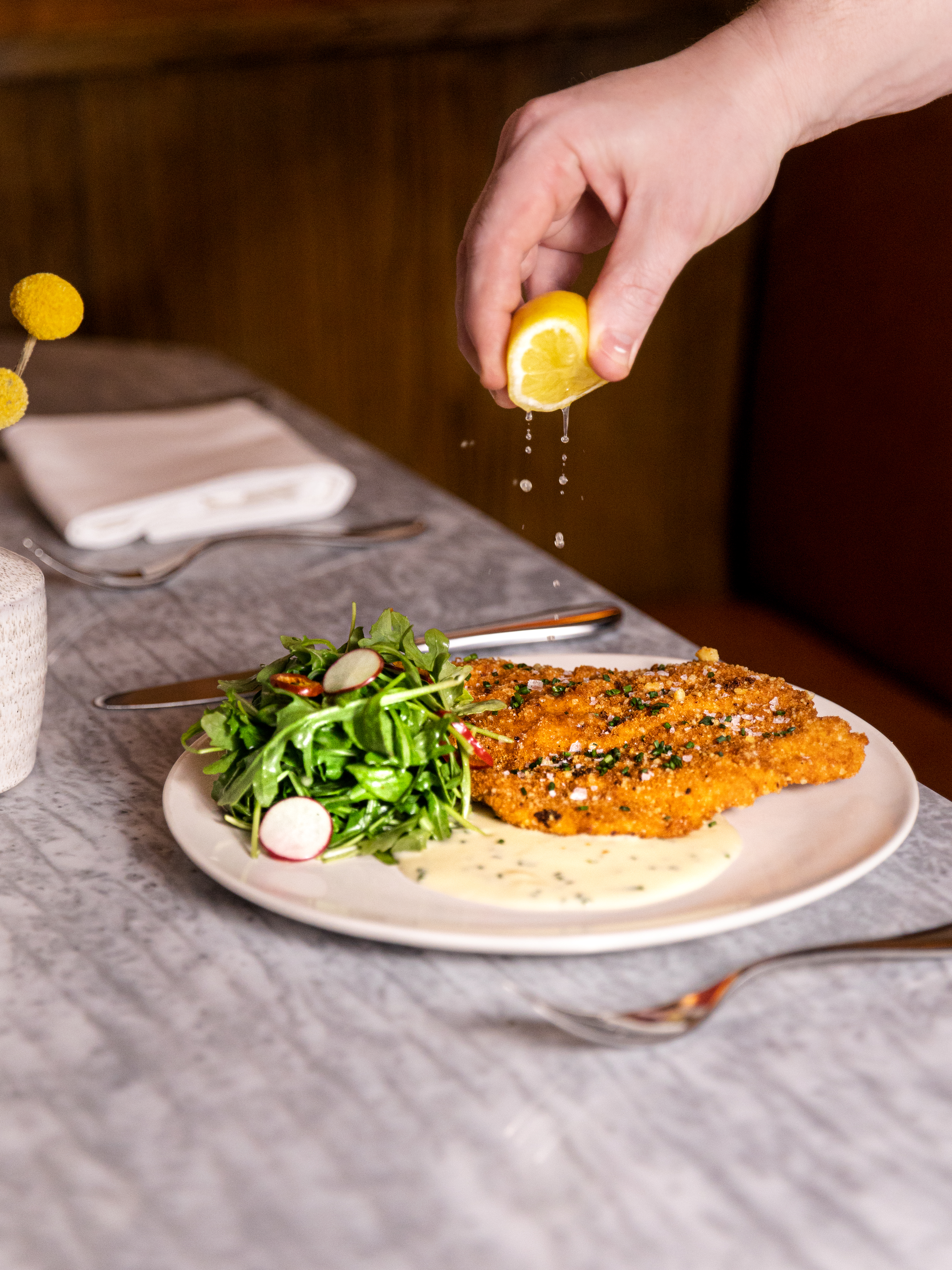 Hand squeezing a lemon over a plate of food