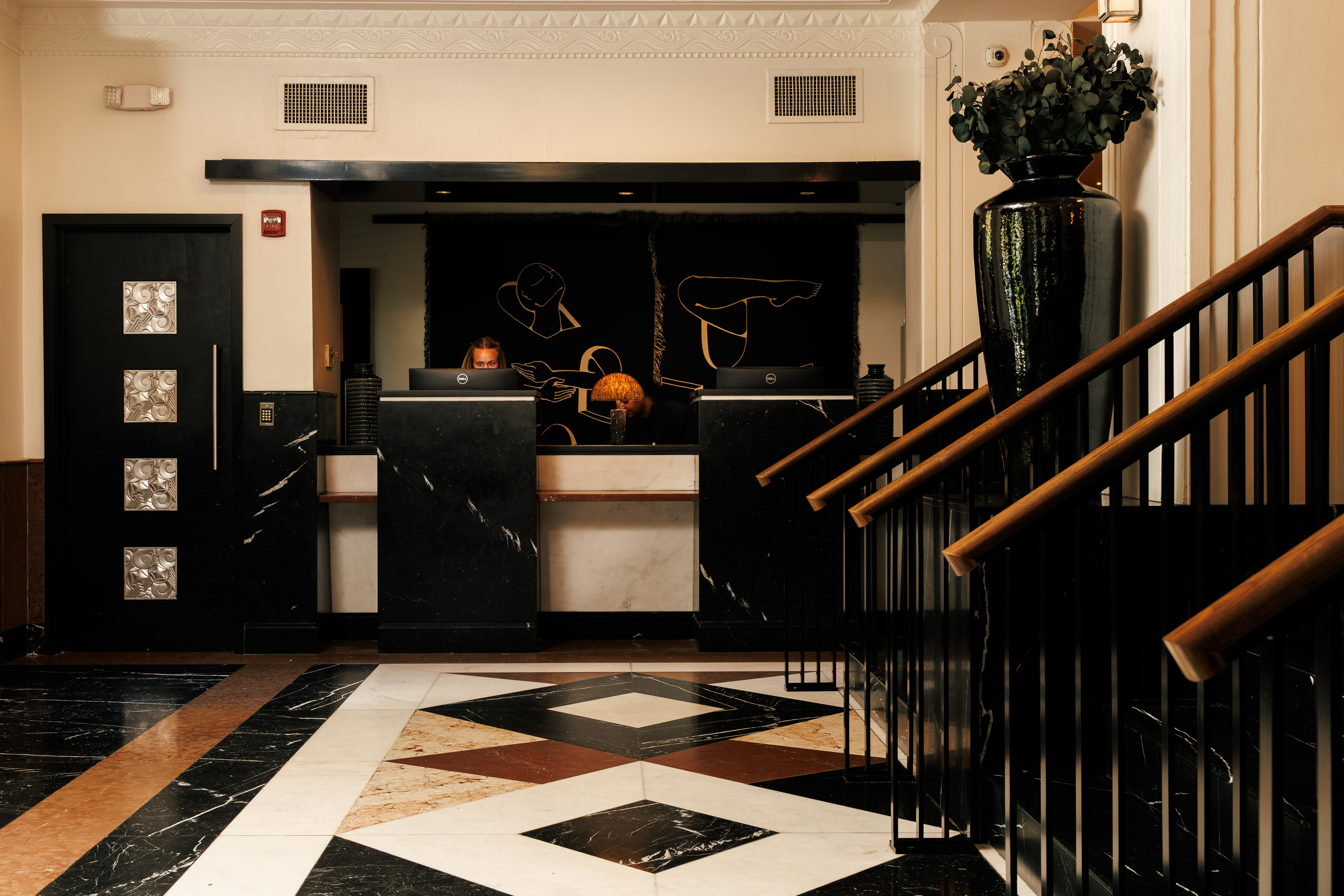 A hotel lobby with a reception desk, staircase, and decorative elements.