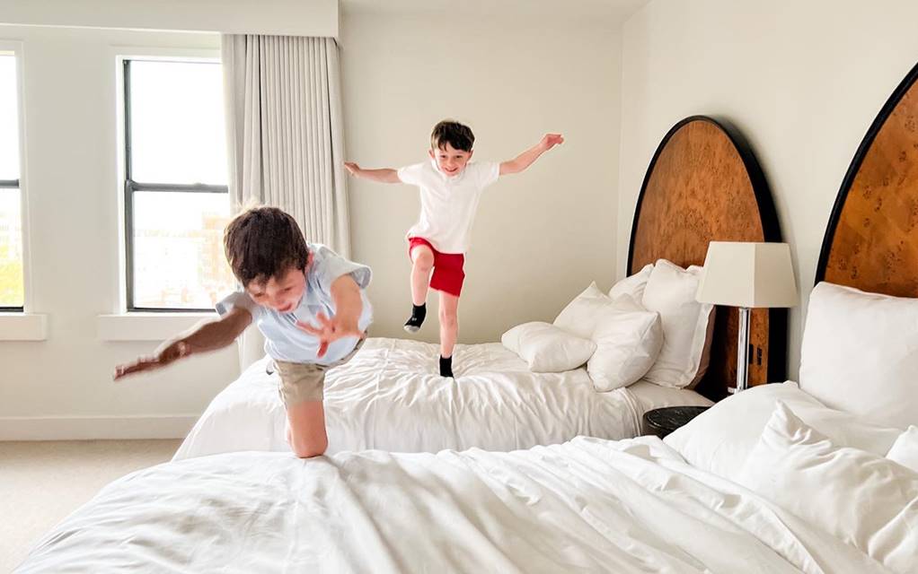 Children jumping on beds in the family-friendly Lyle DC hotel.