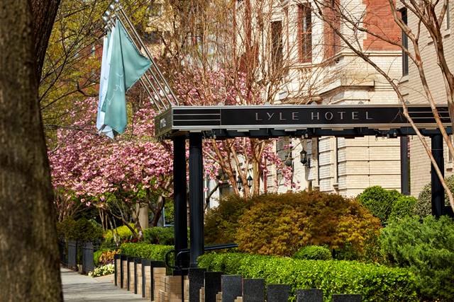 Canopy over entrance of Lyle Hotel, Washington, D.C. with pink blossoms and green bushes.