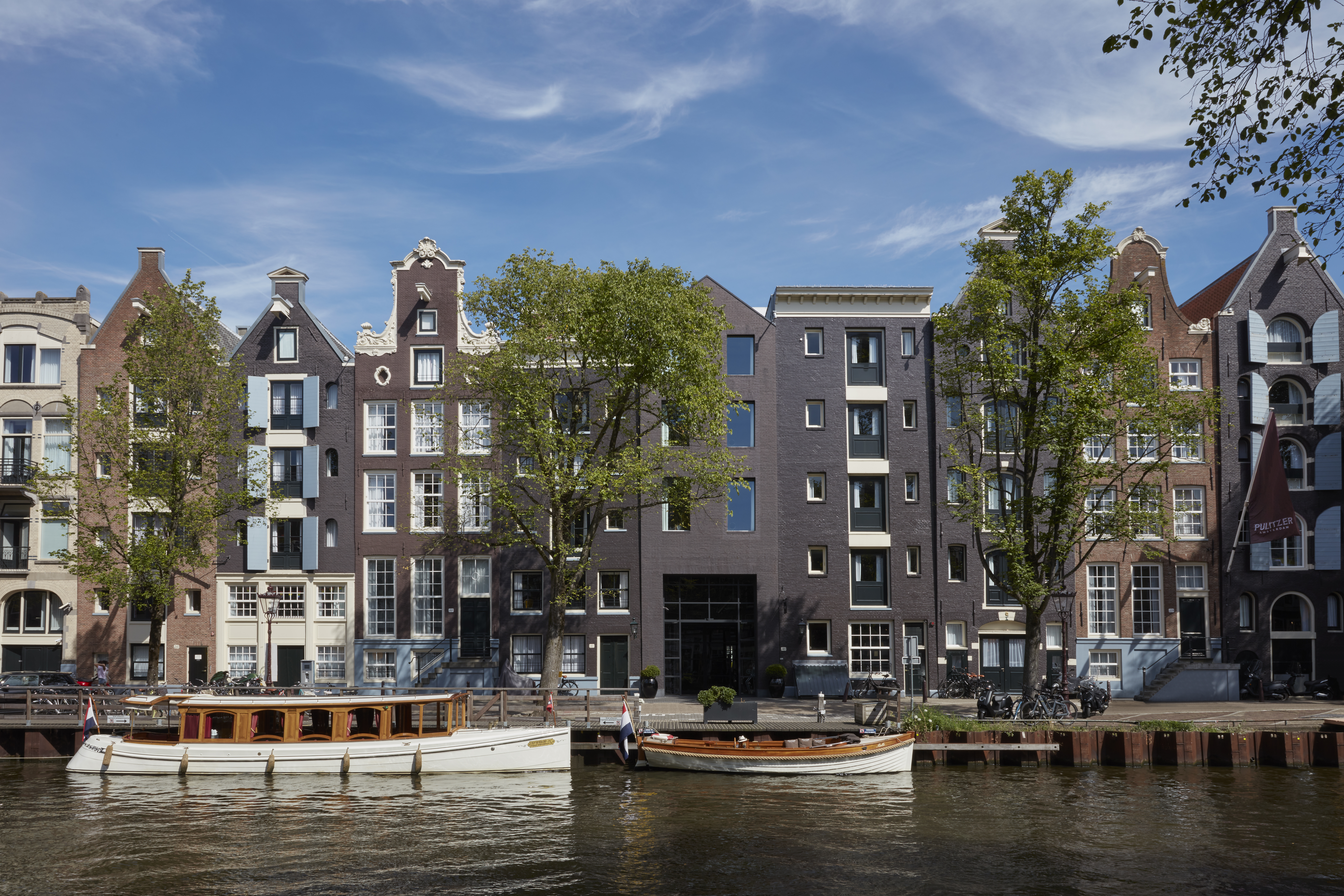 A row of buildings along a canal with boats and trees